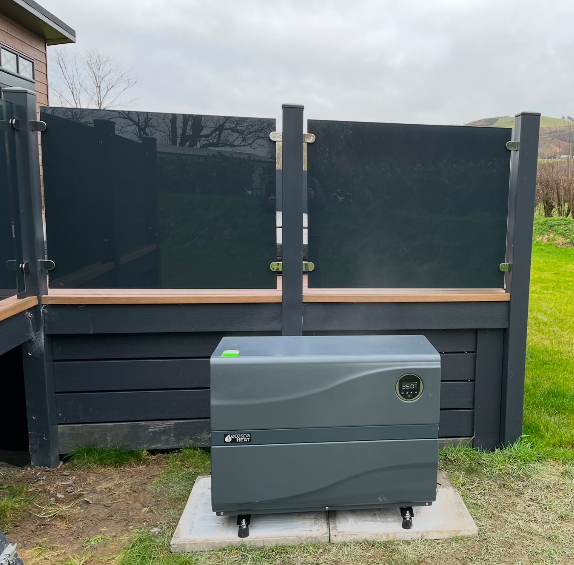 Hot tub heat pump installation by RL Spa beside a modern hot tub (air-source heat pump)