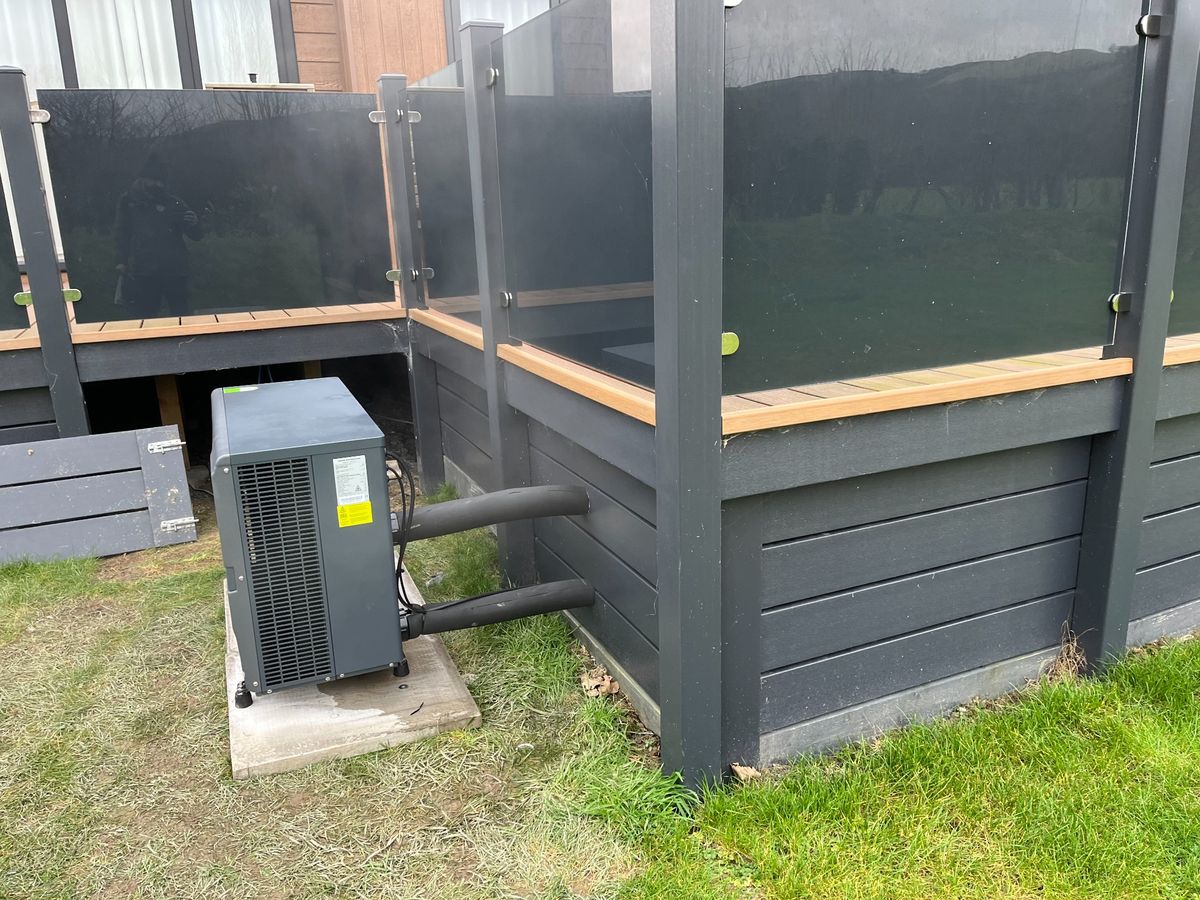 Heat pump beside raised-deck privacy screen — compact outdoor placement by RL Spa