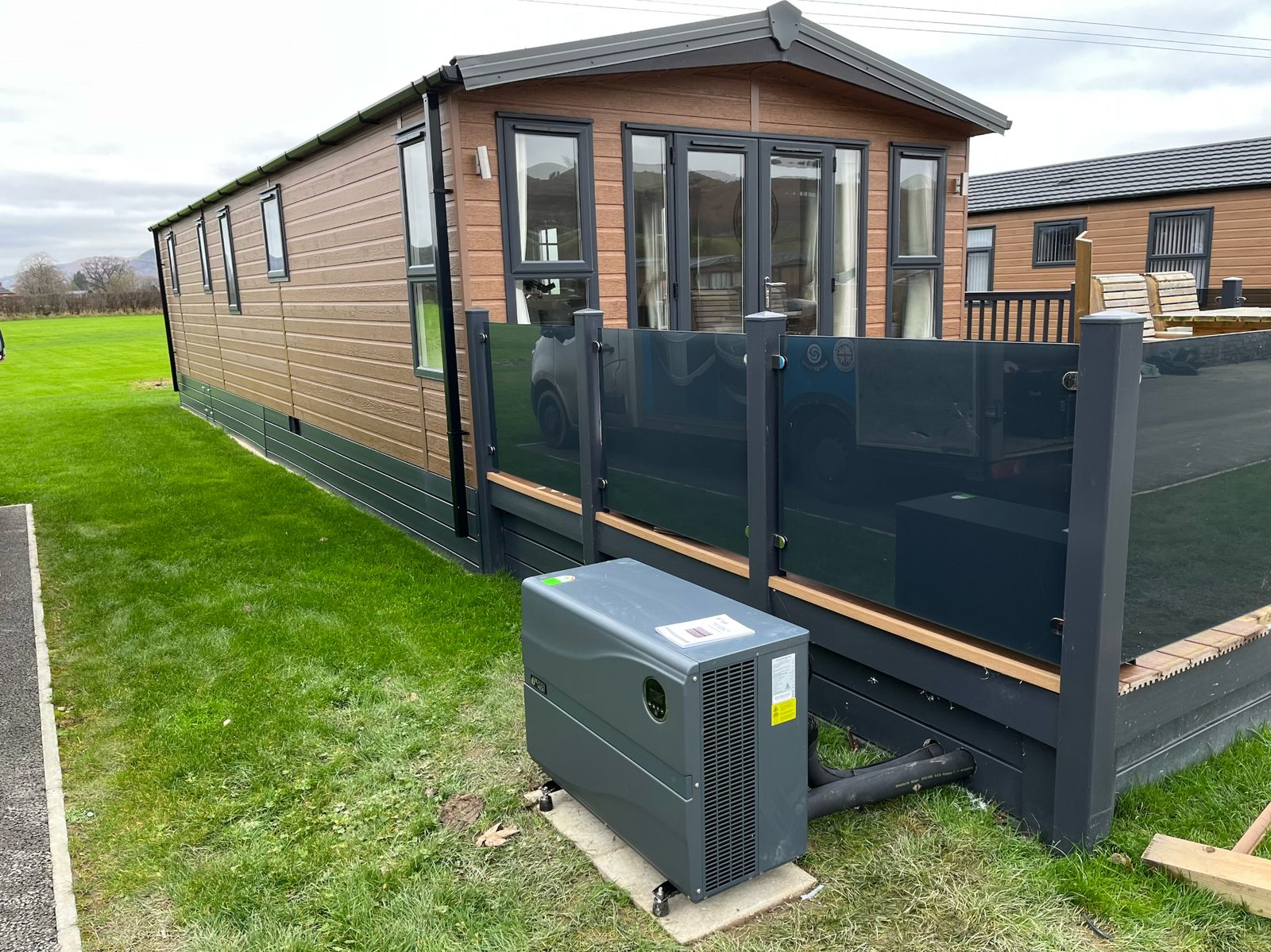 Hot tub heat pump installation at a caravan lodge — compact ASHP unit with insulated flow and return