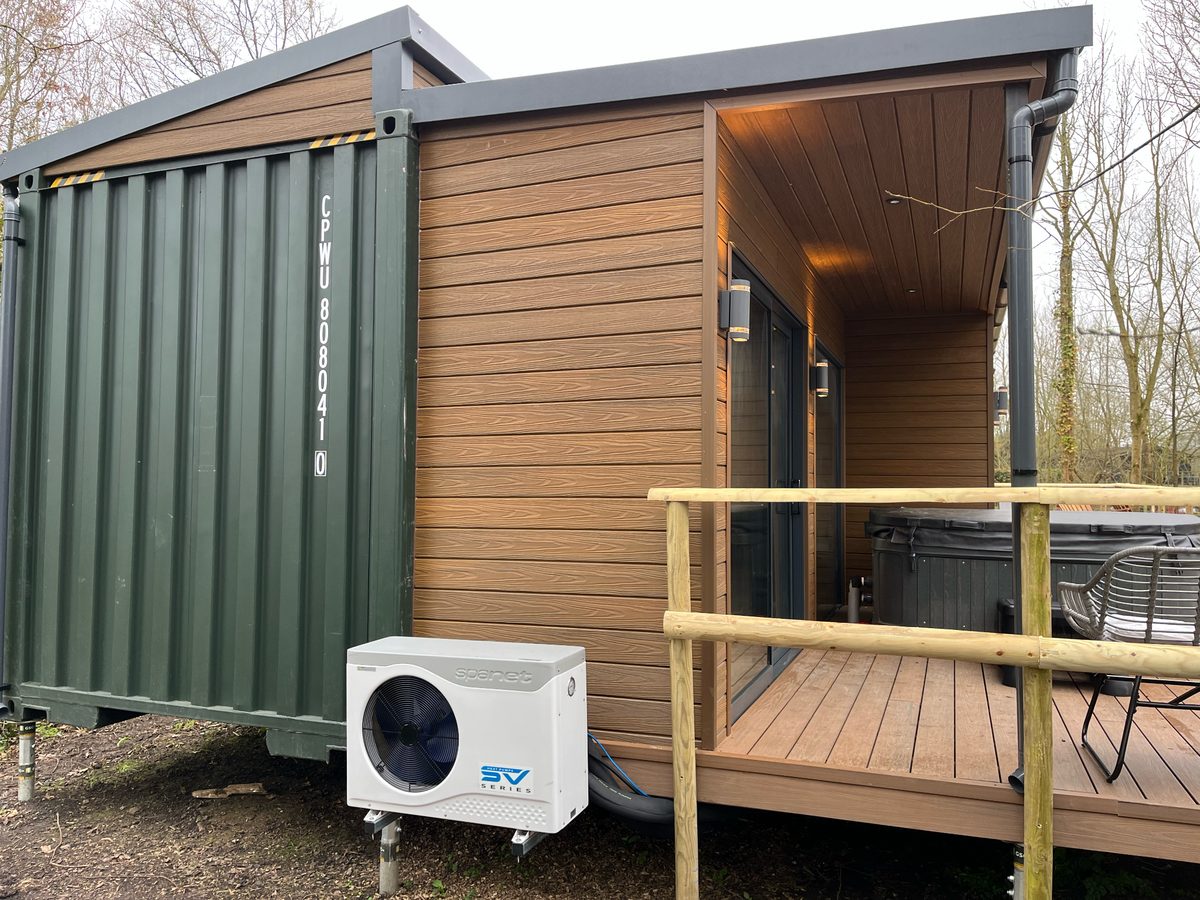 Holiday cabin with hot tub — heat pump mounted neatly beside the deck